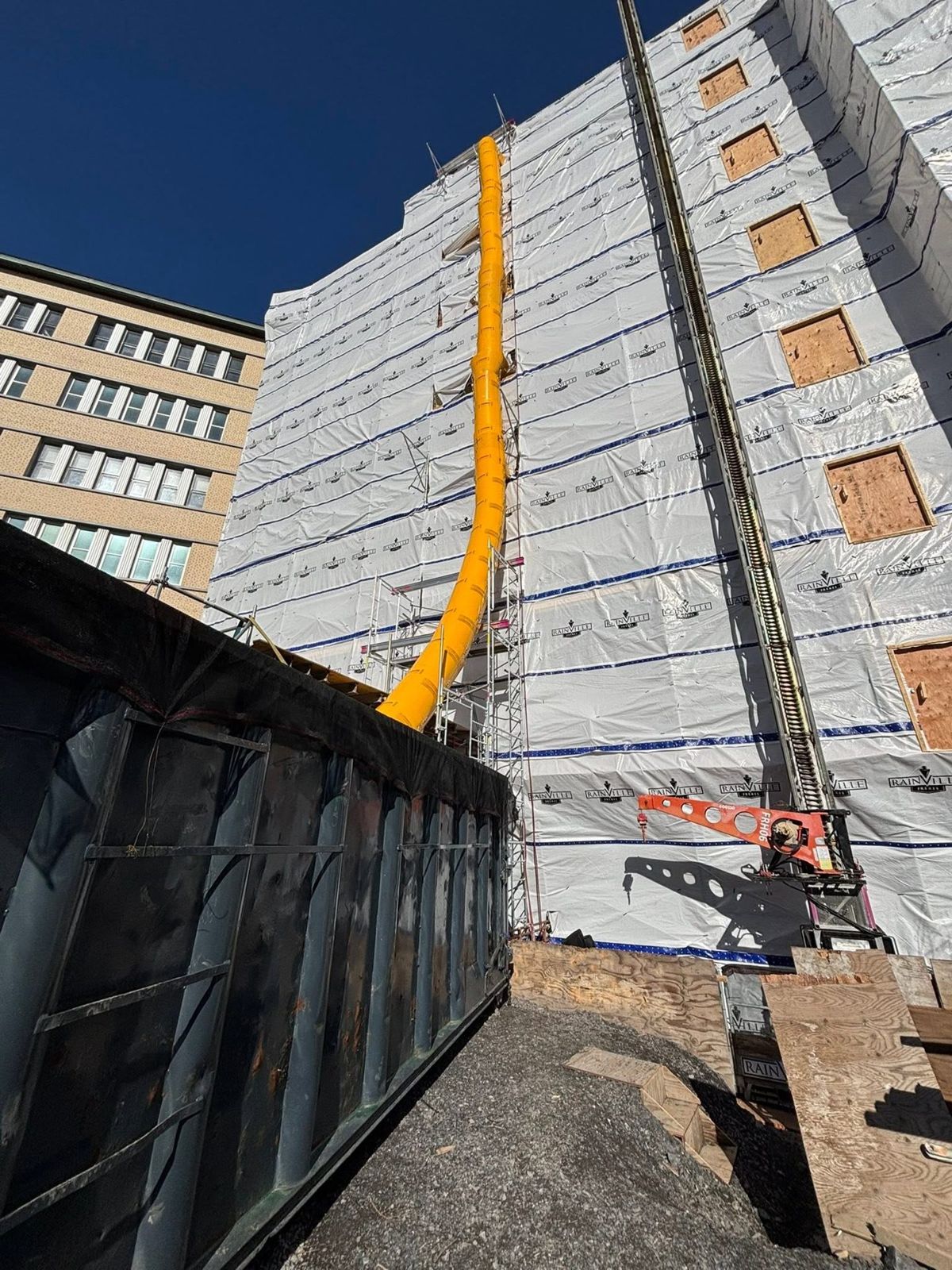 Façade sous bâche avec chute à rebuts jaune